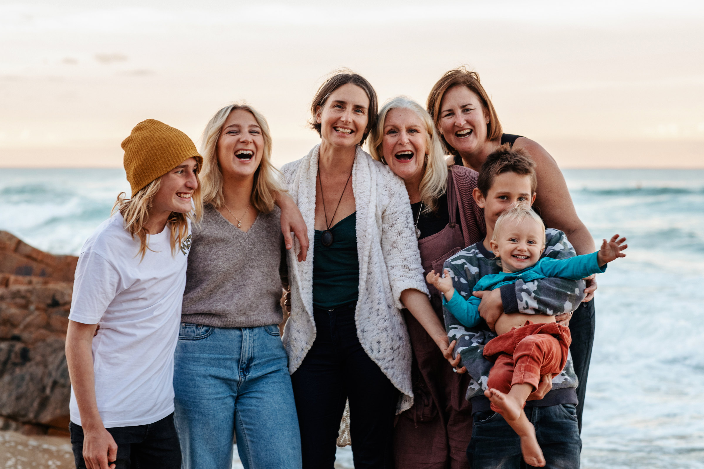 Extended family laughing together beside the ocean