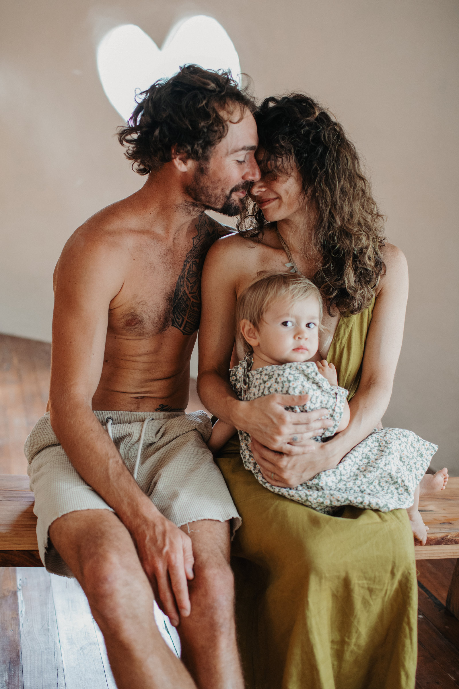 Two adults cuddling a toddler at home